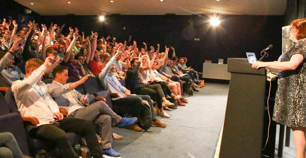 Audience at Collaborate Bristol raising their hands as a speaker asks an open question at the 2017 conference